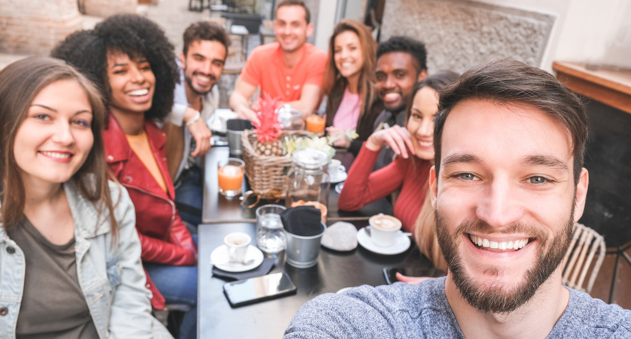 Group of happy friends drinking coffee and cappuccino at bar outdoor - Young millennials people taking selfie while doing breakfast - Friendship, youth and food concept - Focus on right man face