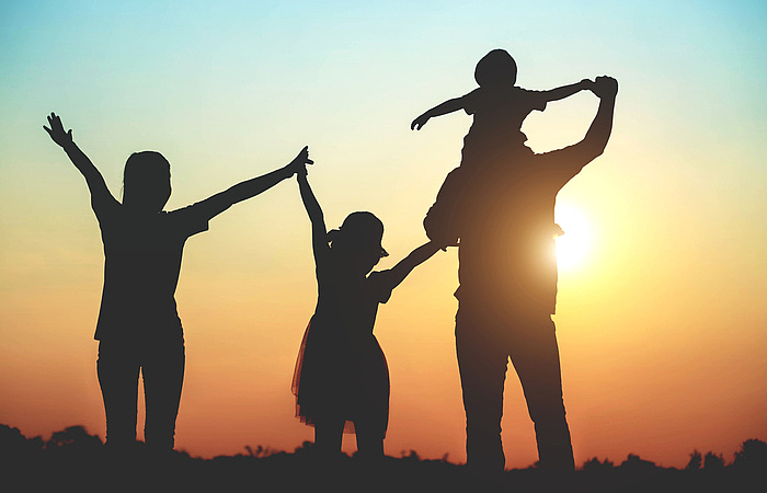 Silhouette of a family comprising a father, mother and two children happy family the sunset.Concept of friendly