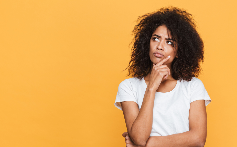 Portrait of a thoughtful young african woman looking away at copy space isolated over beige background